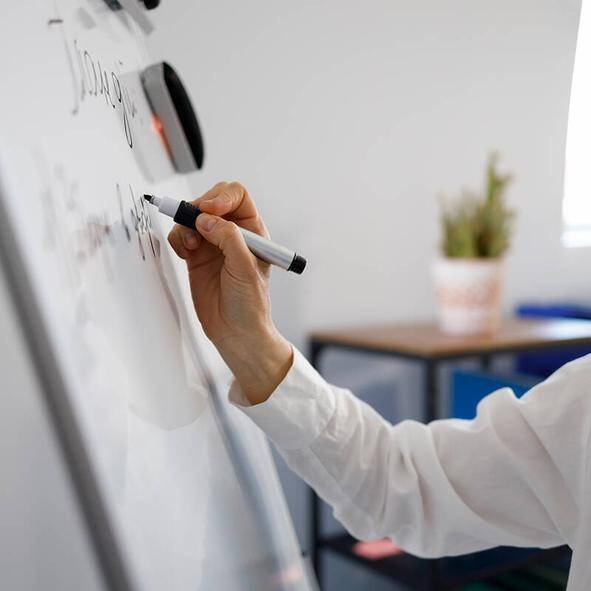 Detailaufnahme einer Hand, die auf einem Whiteboard schreibt – kreative Phase der Eventkonzeption.